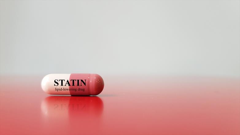 Close-up of an antilipidemic drug capsule displayed horizontally with label reading statin lipid-lowering drug. Close-up of an antilipidemic drug capsule displayed horizontally with label reading statin lipid-lowering drug.